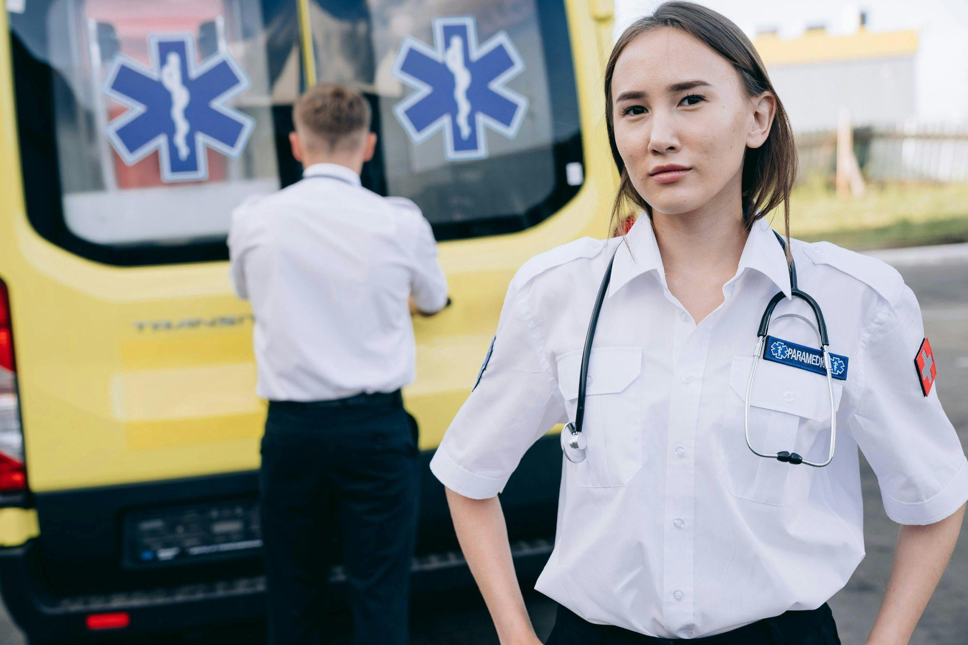 Paramedic standing by ambulance, another preparing