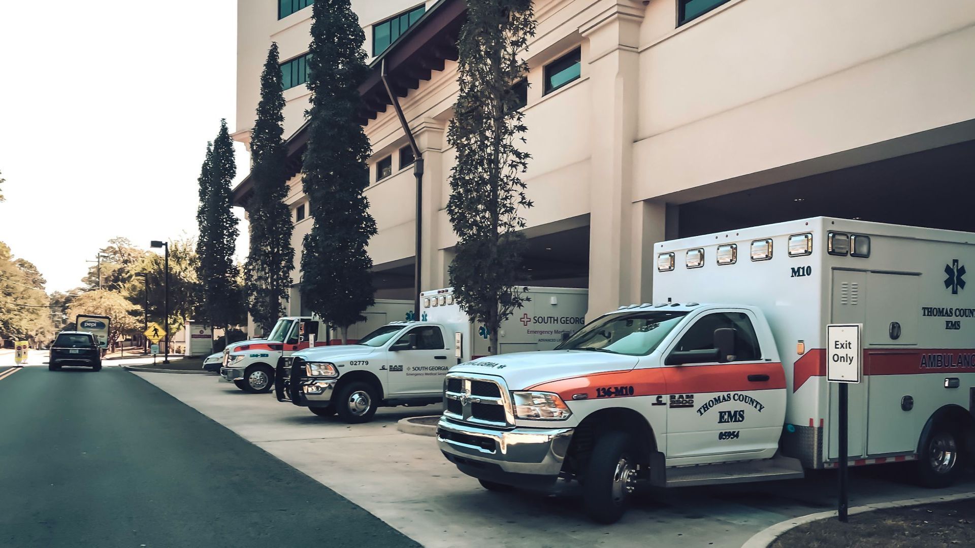 Multiple ambulances parked outside a hospital entrance